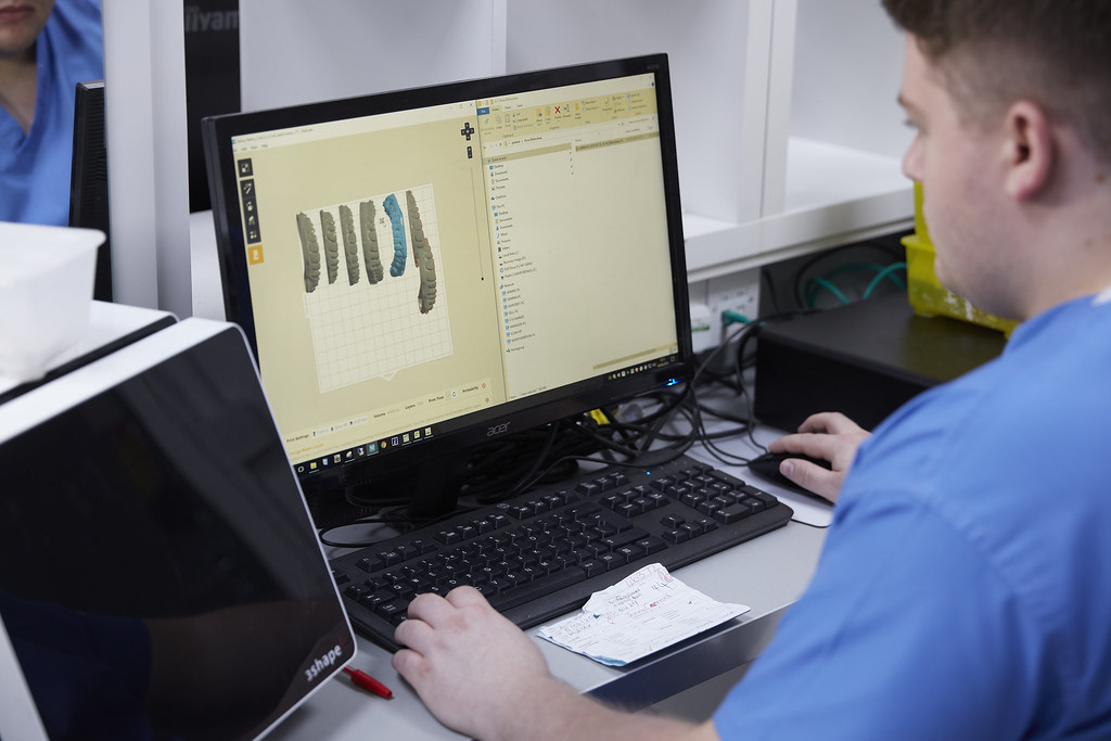 Dental technician designing a 3D teeth model in CAD software at a workstation